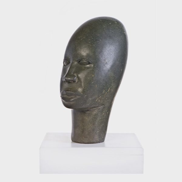 Skulpturen-Kopf eines jungen, afrikanischen Mannes aus grauem Serpentinstein auf weißem Sockel